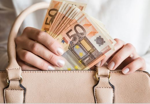 Ein Mann Steckt 50 Euro Scheine in eine Ledertasche.